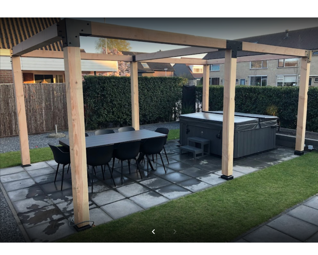 Houten pergola met metalen koppelstukken, geplaatst boven een eettafel en jacuzzi. Robuuste Douglas constructie ideaal als luxe buitenoverkapping in de tuin.