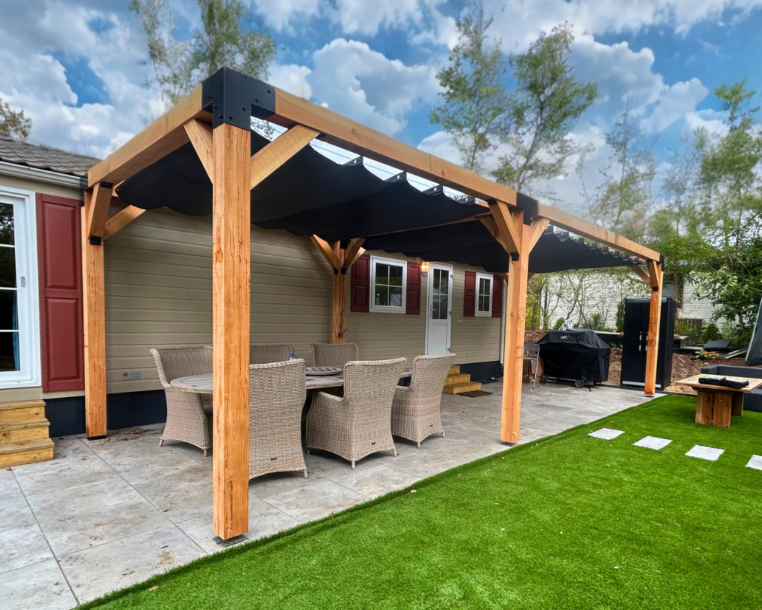 Dubbele houten pergola met zwart harmonicadoek aan een chalet. Luxe terrasoverkapping van Douglas hout met stevige metalen koppelstukken, ideaal voor een sfeervolle zonwering buitenruimte